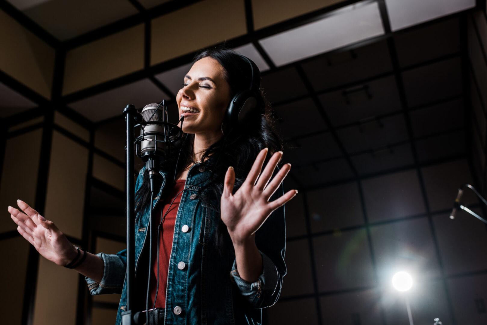 Attractive inspired woman singing near microphone in recording studio