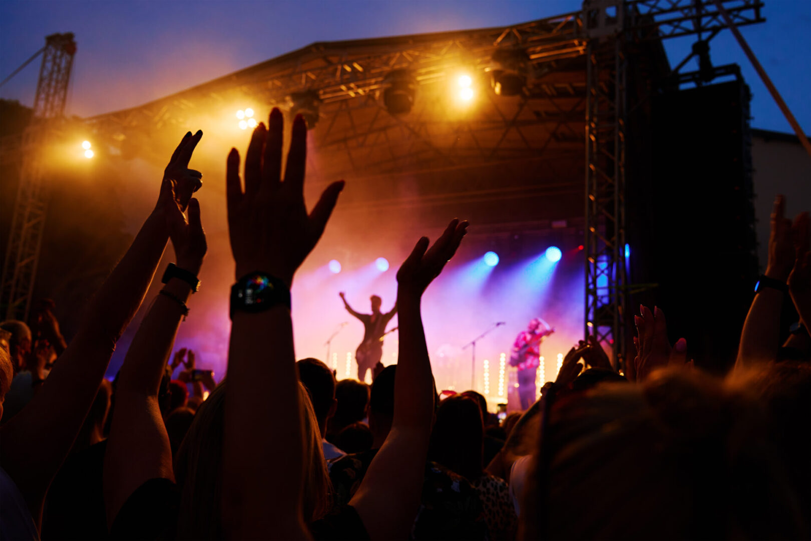 Crowd of people enjoying concert before stage with bright spotlights